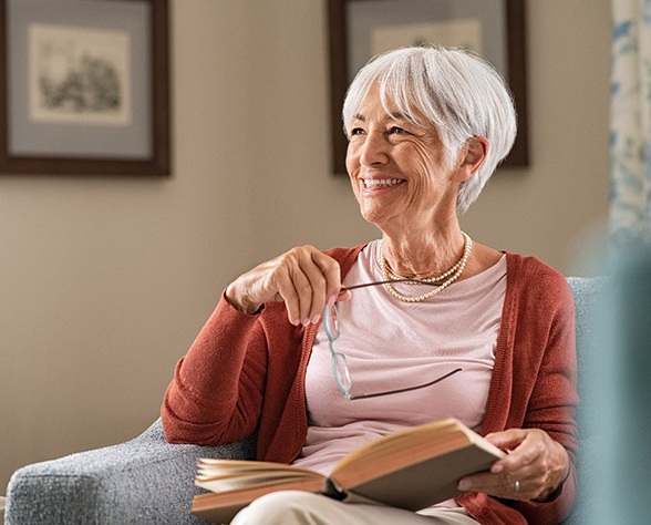 Senior woman sitting in chair reading book