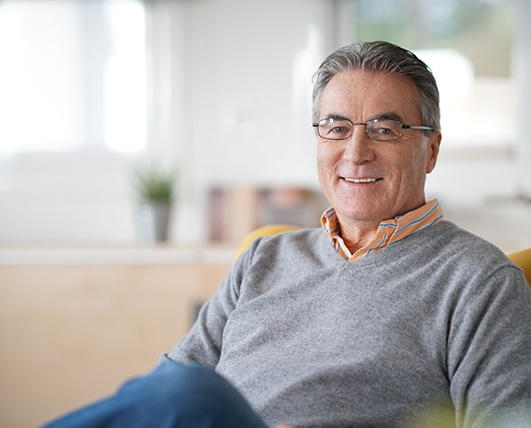 Man with glasses and grey shirt sitting on couch