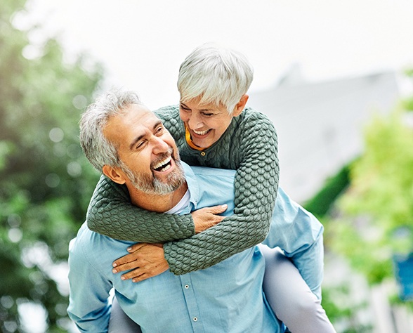 Senior man carrying senior woman on back