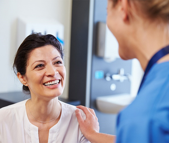 Woman examining smile in mirror after periodontal treatment