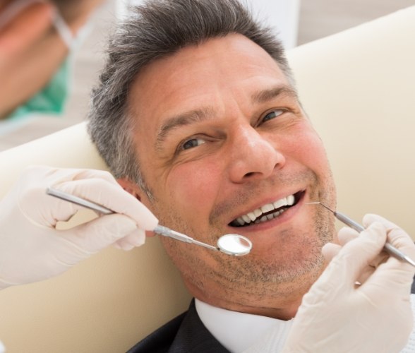 Man smiling during dental checkup to prevent periodontal emergencies