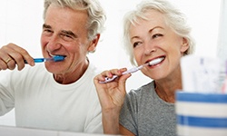 older couple brushing their teeth in bathroom