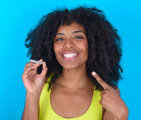 Happy woman holding clear orthodontic aligner
